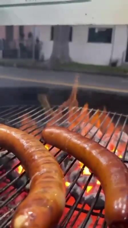 Two sausages over open flames on the charcoal grill
