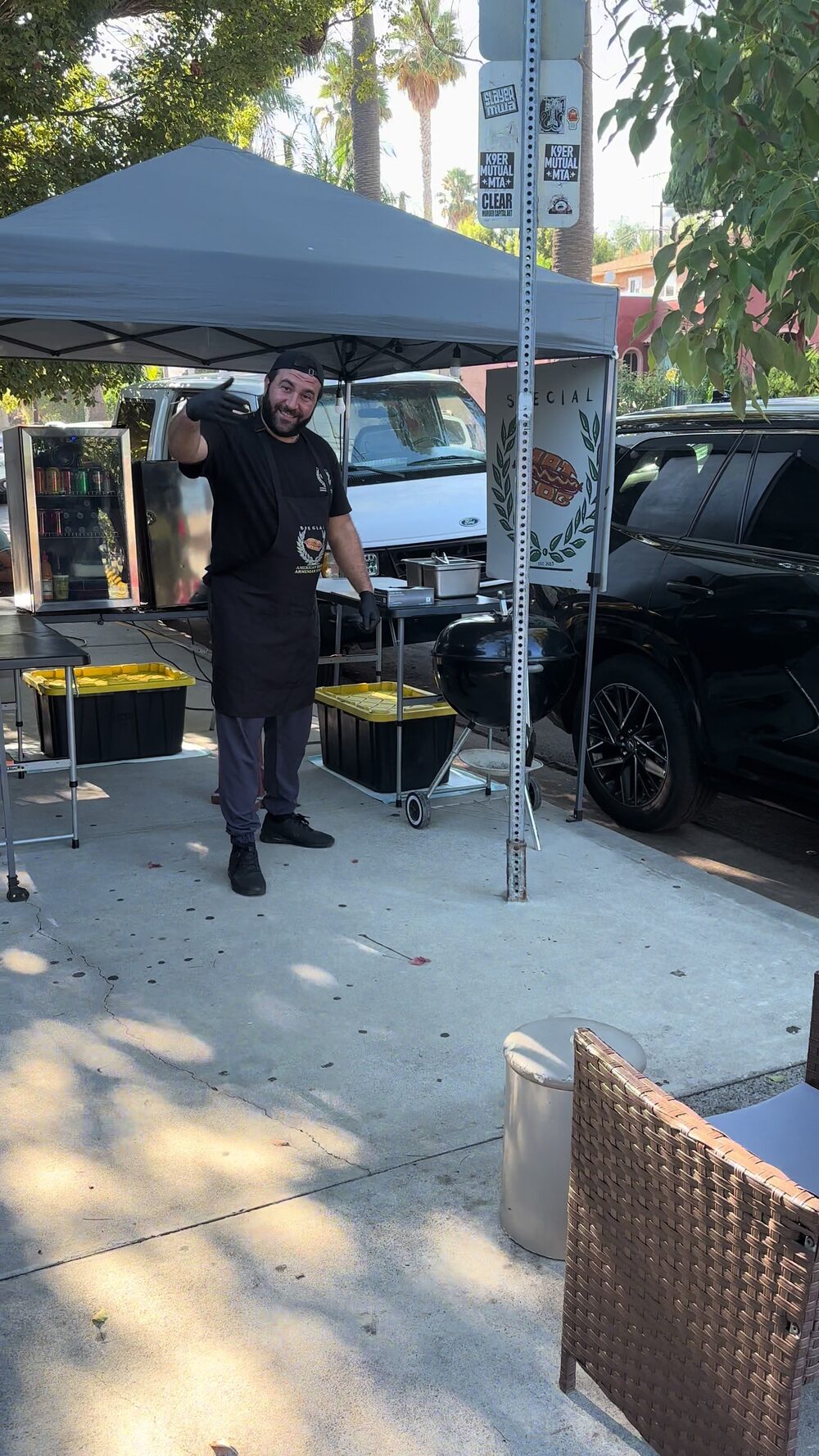 The Special Hot Dog stand under its tent on the sidewalk, with a wave from behind the grill